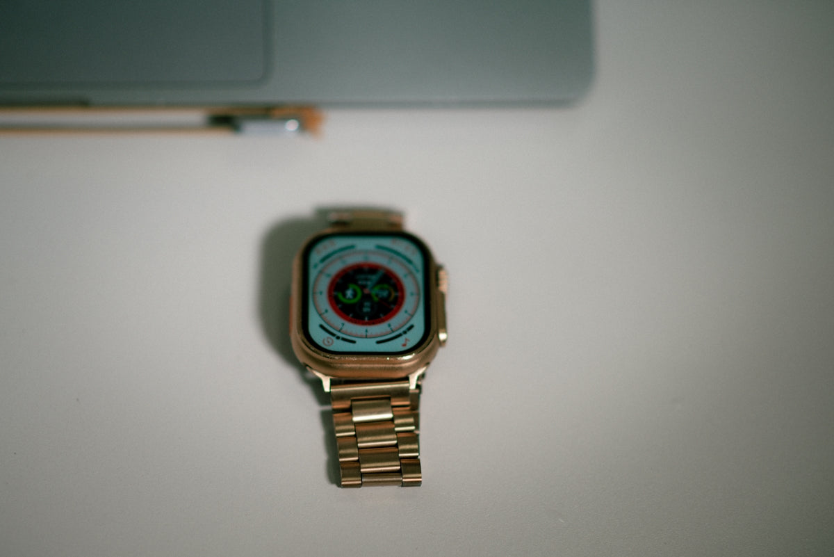 a watch sitting on top of a table next to a laptop